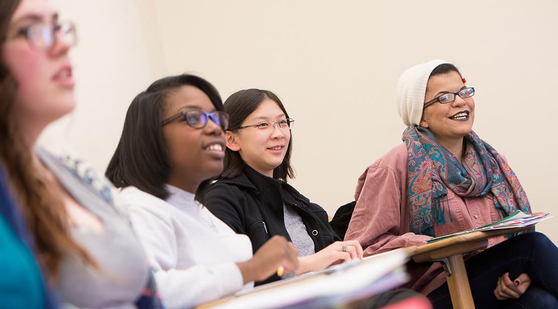 Students in classroom, smiling looking toward front of room.