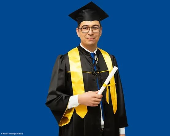 MBA Alumnus Ibrokhimkhon Akhmadkhonov in his commencement gown looks into the camera