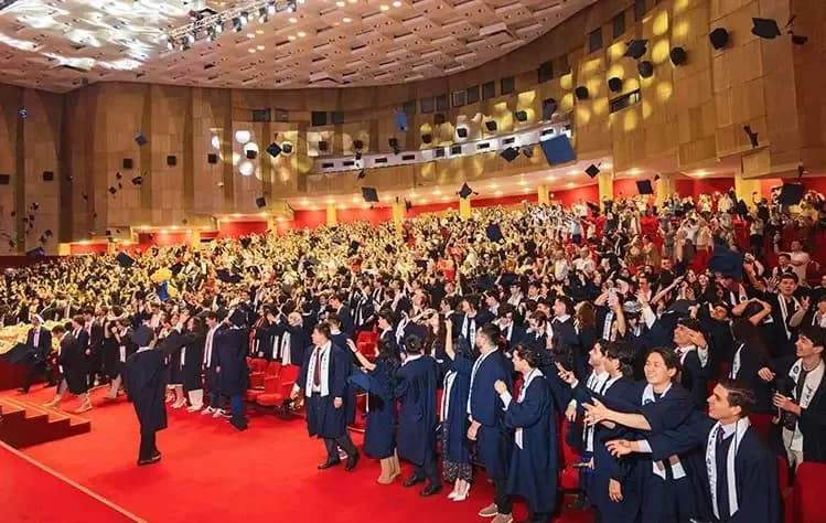 Graduates celebrating Commencement by tossing their graduation caps into the air, smiling and cheering together as they mark the completion of their academic journey.