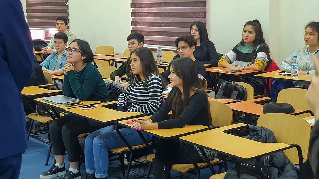 Classroom full of students listening intently to professor in front.
